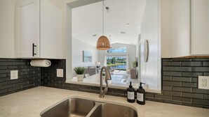 A modern kitchen with a double sink, black tiled backsplash, and a hanging light fixture. - Huge Pool, Near Beaches, IMG, UTC, Great Clubhouse (Bradenton)