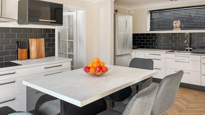 A modern kitchen with white cabinets, a marble countertop, and a fruit bowl. - Lamp Post Cottage 3 - UK50955 (Bridlington)