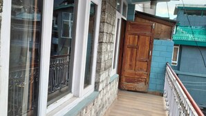 A narrow corridor with stone walls, wooden door, and a metal railing.