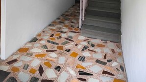 A hallway with a tiled floor, a staircase, and a door at the end.