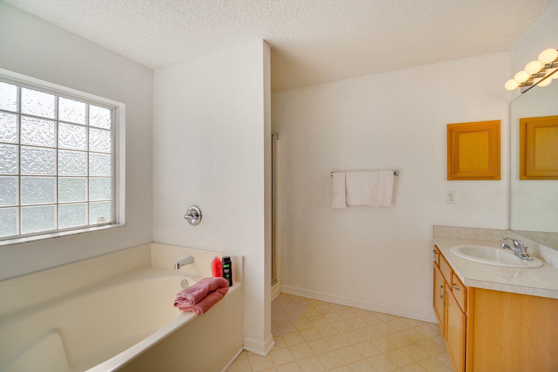A bathroom with a bathtub, a shower, a sink, and a window.