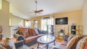 A living room with a sofa, armchairs, a coffee table, a ceiling fan, a TV, and a glass cabinet. - Stay In peace and rlx (Brevard County)