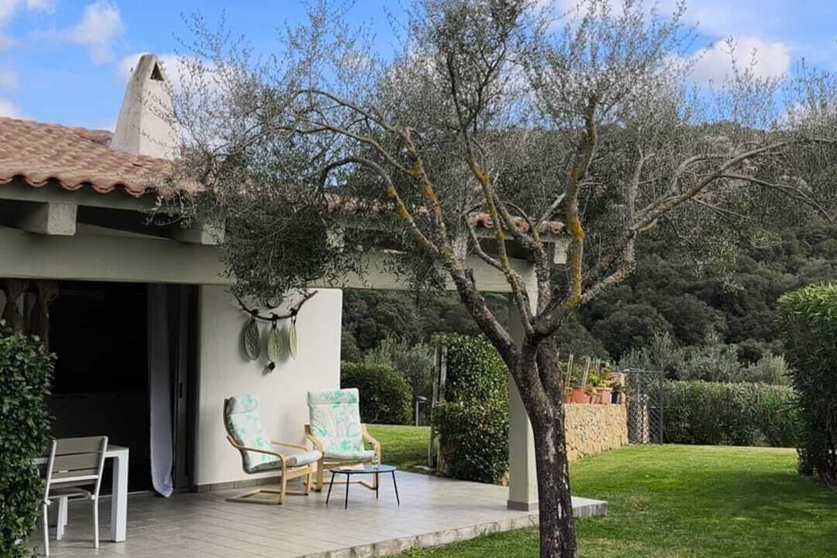 Ein Haus mit Terrasse, Sitzgelegenheit im Freien und einem Baum im Garten.