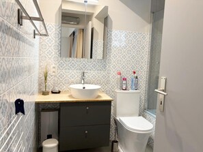 A bathroom with a white sink, dark cabinet, toilet, and patterned tiles. - Cozy Coastal Apartment With Dual Terraces (Middelkerke)