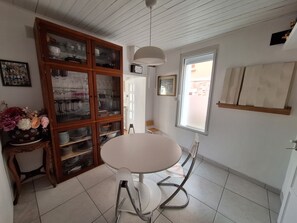 Ein Essbereich mit rundem Tisch, Stühlen, einer Vitrine mit Glastüren, einer Hängeleuchte und einem Fenster mit Aussicht.
