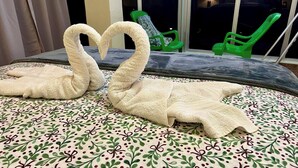 Una cama con una colcha de estampado floral y dos toallas con forma de cisne.