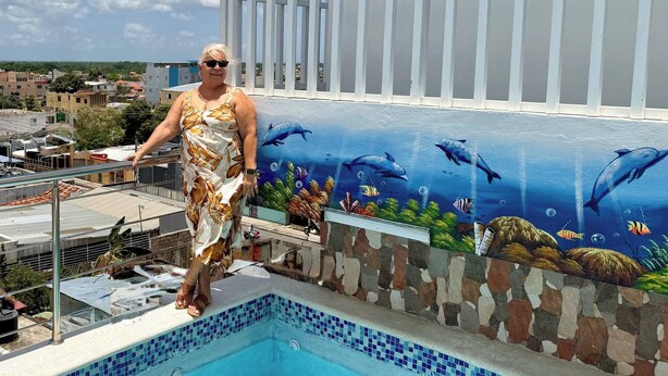 Una persona está de pie junto a una piscina con un mural de vida marina.