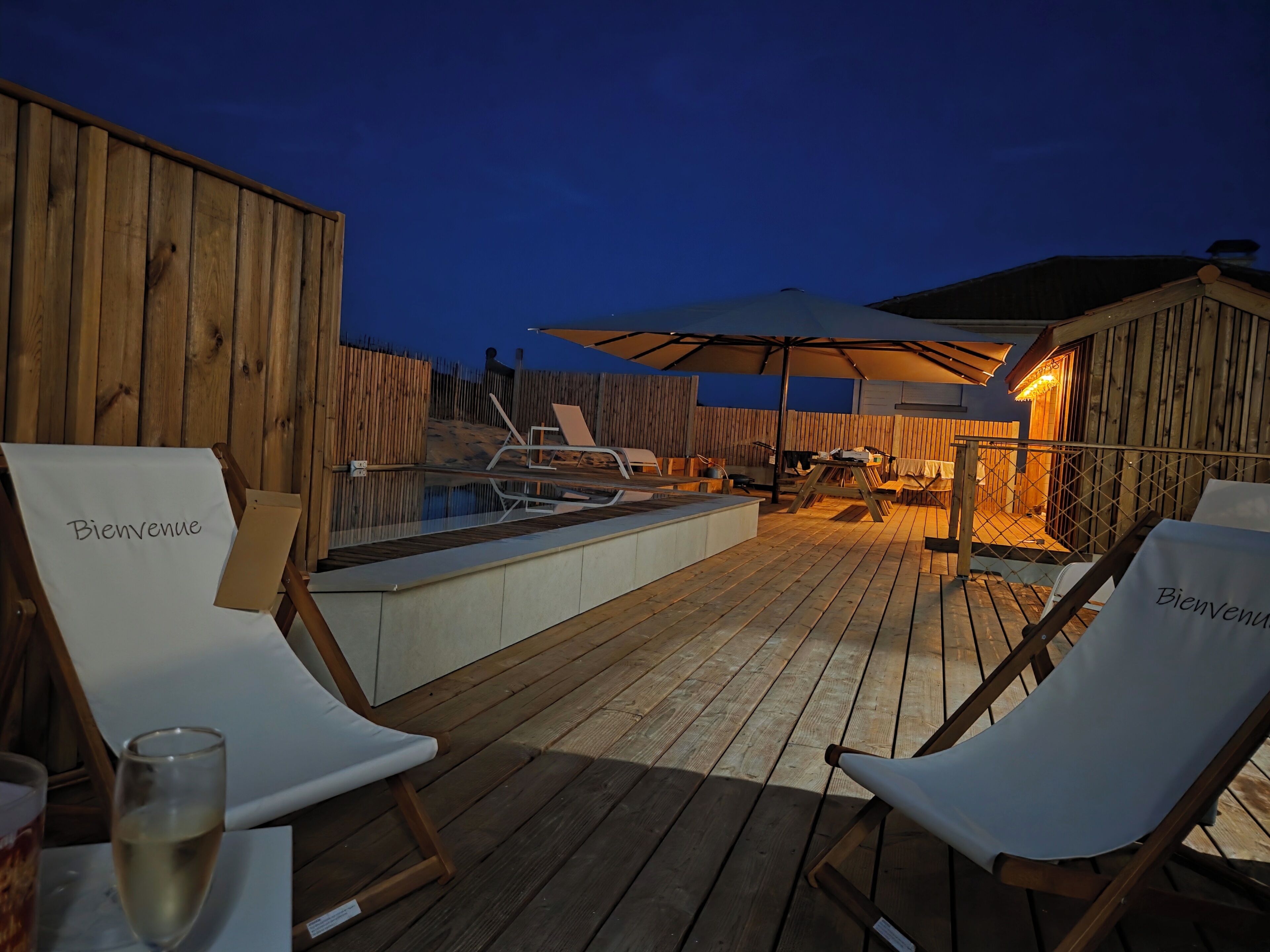 A wooden deck with lounge chairs and a pool area.