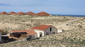 A coastal area with sandy terrain and buildings with red roofs.