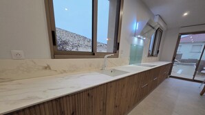 A modern bathroom with a marble countertop, wooden cabinets, a sink, and a large window.