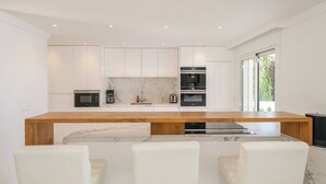 Una cocina moderna con armarios blancos, encimera de madera y horno empotrado.