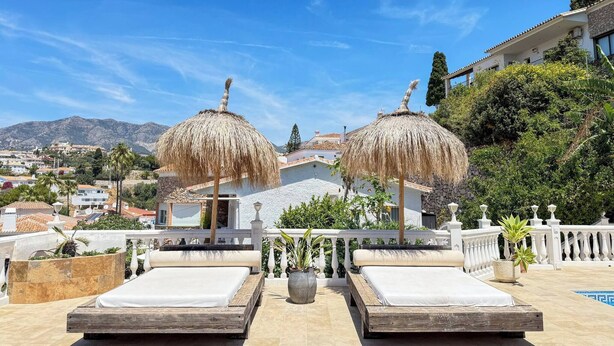 Terraza en la azotea con dos camas, una piscina y vistas a la ciudad y las montañas.
