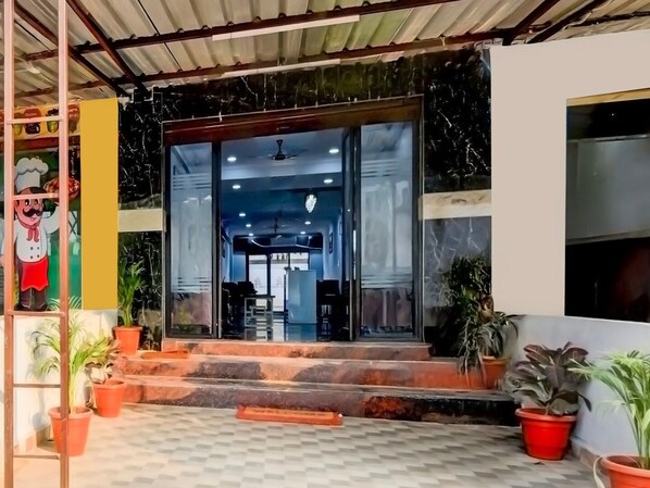 A building entrance with a glass door, steps, and potted plants.