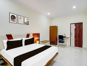 Una habitación de hotel con cama, escritorio, armario y puerta.