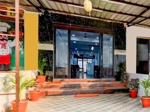 A building entrance with a glass door, steps, and potted plants.