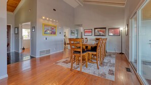 A dining area with a wooden table and chairs, framed artwork on the walls, and a view through a glass door. - San Diego Hilltop Haven: Game Room+Views! 18 Minutes from Downtown (Spring Valley)