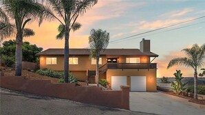 A two-story house with a balcony, a garage, and a driveway. - San Diego Hilltop Haven: Game Room+Views! 18 Minutes from Downtown (Spring Valley)
