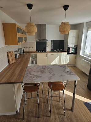 A modern kitchen with a marble countertop, wooden cabinets, and a central island with chairs. - House 3bed Terraces Jacuzzi Garden 4min from the beach. (Cléder)
