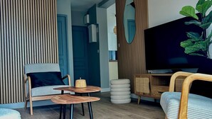 A modern living room with a sofa, a coffee table, a TV, and a large plant.