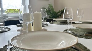 A dining table set with plates, cutlery, and wine glasses, with a candle and a framed picture on the wall.