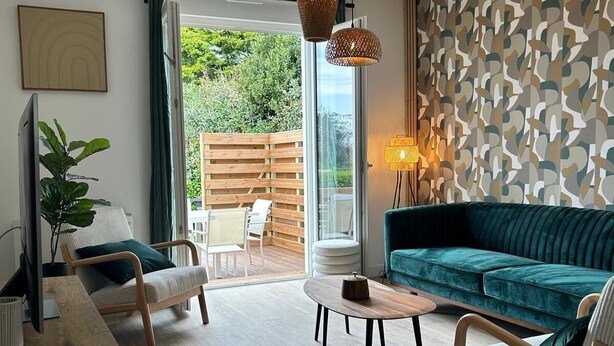 A modern living room with a sofa, chairs, a coffee table, and a TV.