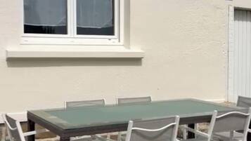 Un edificio con un amplio ventanal, un cartel con el número 14, y una mesa con sillas en el exterior.