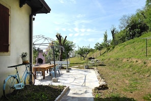 Une terrasse avec une table et des chaises, un vélo et une petite cuisine d’extérieur.