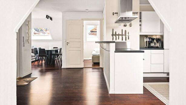 Una cocina moderna con armarios blancos, una isla central y un comedor con mesa y sillas.