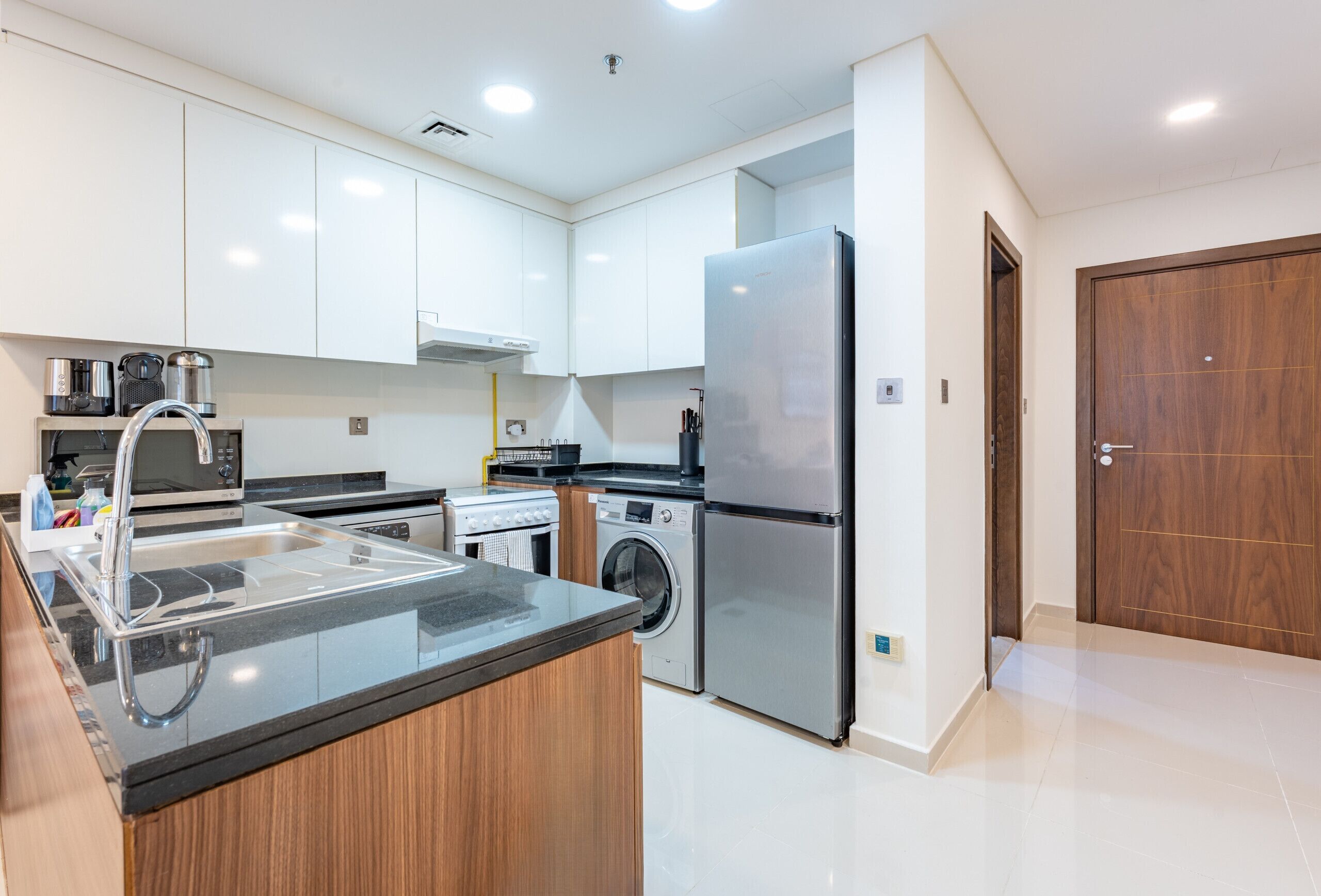 A modern kitchen with stainless steel appliances, a washing machine, and a wooden island.