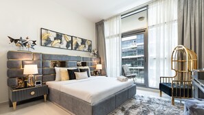 Ein modernes Schlafzimmer mit einem großen Bett, einem Nachttisch mit Lampe, einer Wanddekoration und Blick auf die Stadt durch große Fenster.