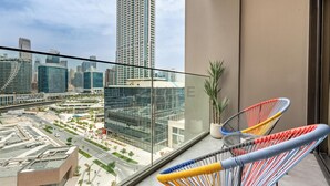 Ein Balkon mit Blick auf die Stadt, zwei farbenfrohe Stühle und ein Blumentopf.