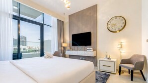 A modern hotel room with a large bed, a television, a clock, and a city view. - Cozy Modern Studio Just A Quick Drive from Meydan Racecourse, Azizi Riviera 20 (Dubai)