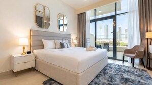 A modern hotel room with a large bed, a nightstand, a chair, and a view of the city through large windows. - Cozy Modern Studio Just A Quick Drive from Meydan Racecourse, Azizi Riviera 20 (Dubai)