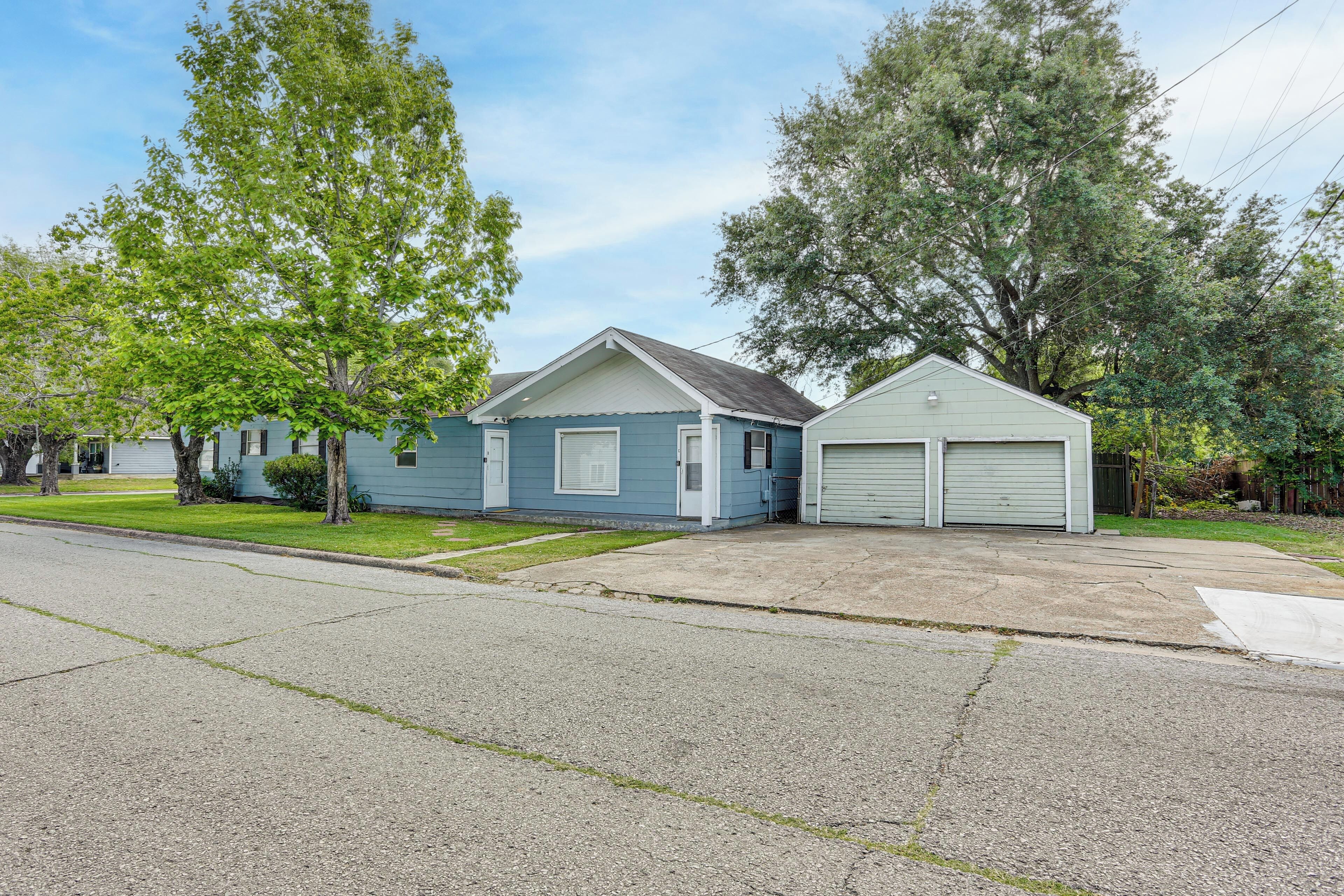 A residential house with a garage, a front lawn, and trees.