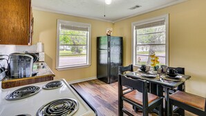 Una cocina con estufa, refrigerador y mesa de comedor con sillas.