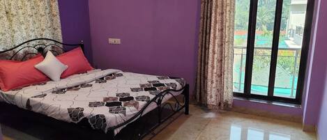 A room with a bed, purple walls, a window with curtains, and a view of greenery outside.