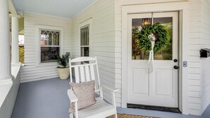 Un portico in legno bianco con una panchina e una porta decorata con una ghirlanda.