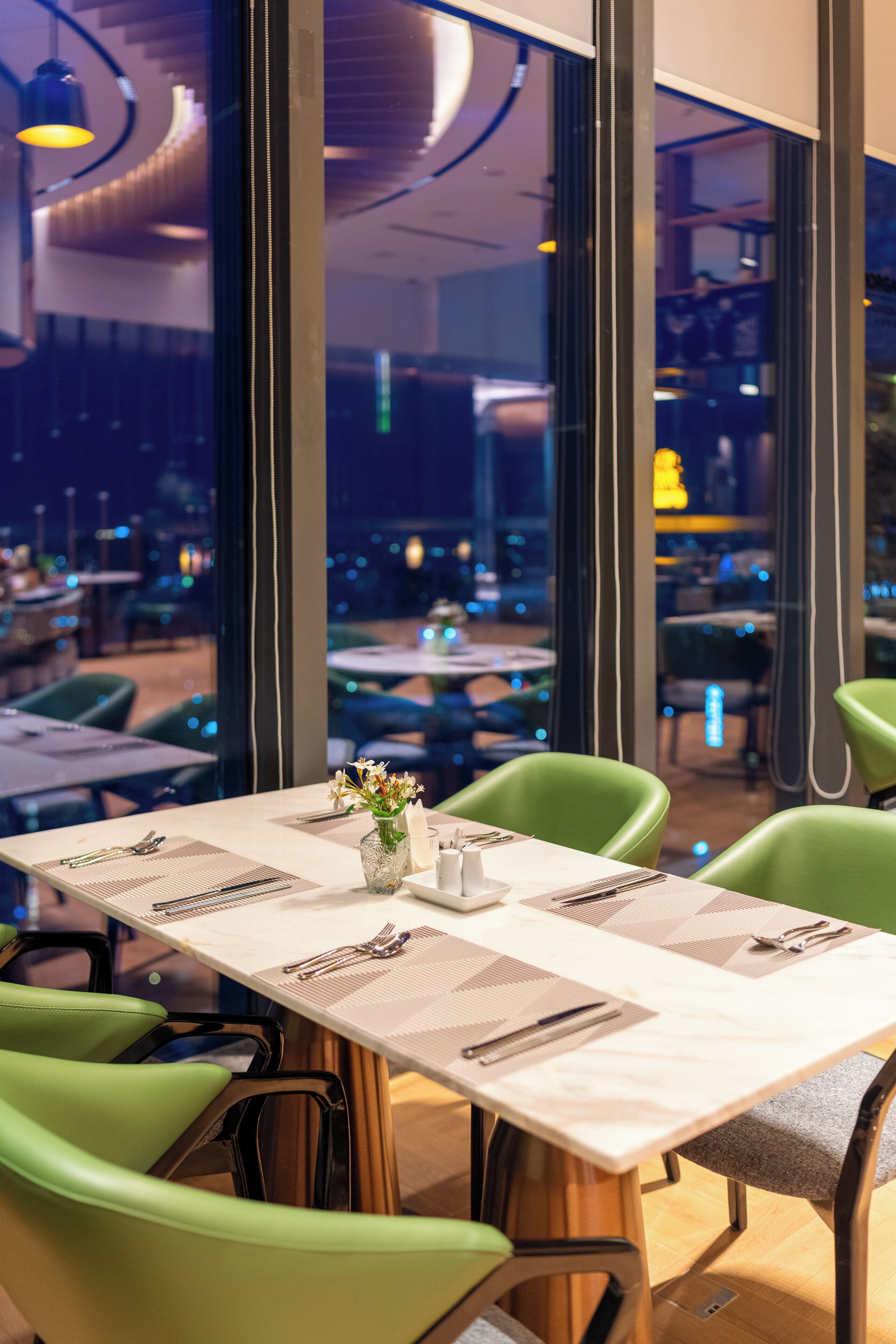 Un restaurant avec une table réservée pour deux personnes, de grandes fenêtres et une vue sur le paysage urbain.