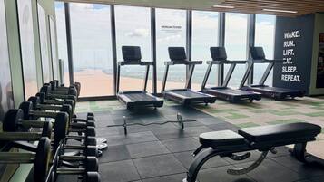 A gym with treadmills, dumbbells, and a bench.