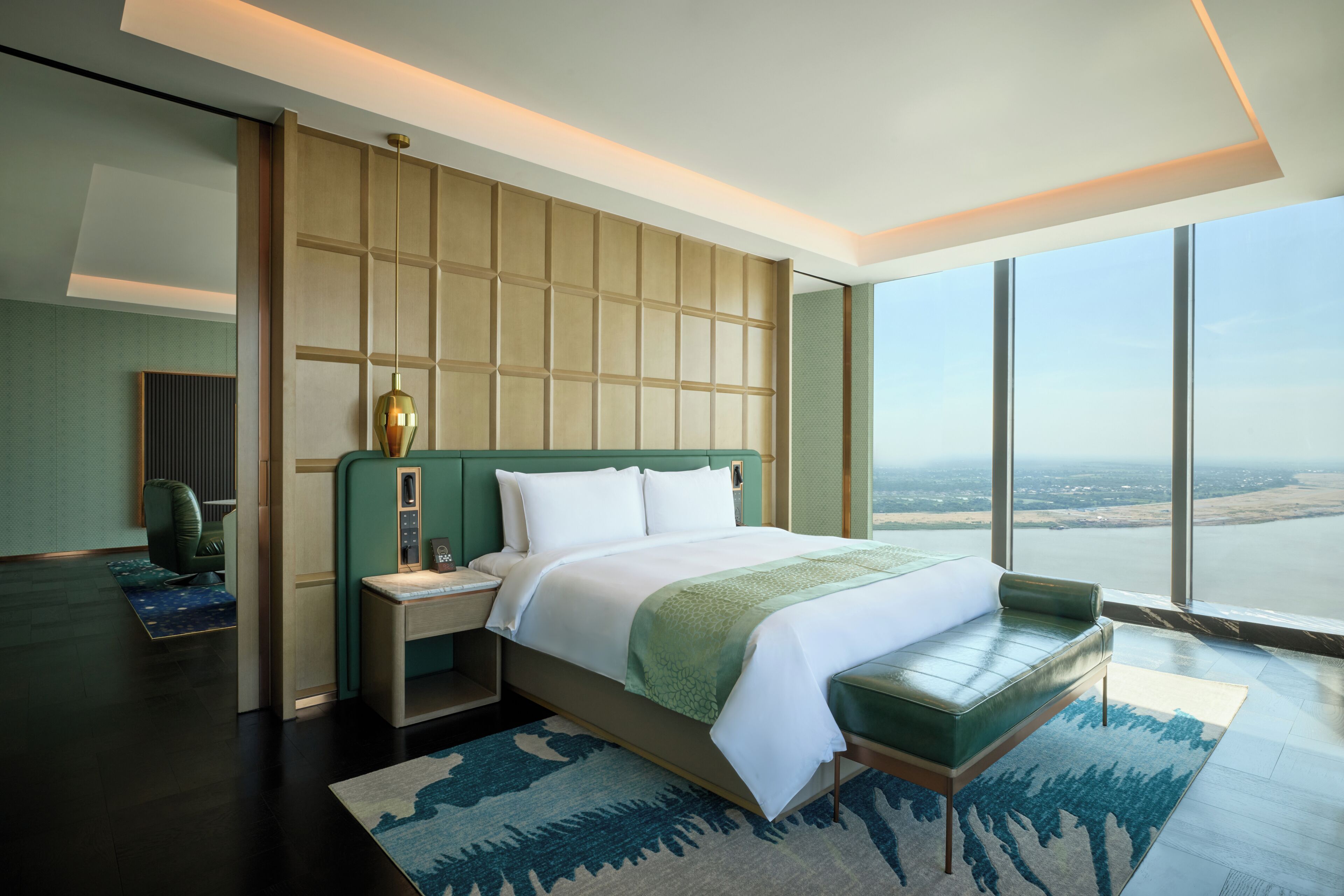 Ein modernes Hotelzimmer mit einem großen Bett, Blick auf die Stadt und einer grünen Akzentwand.