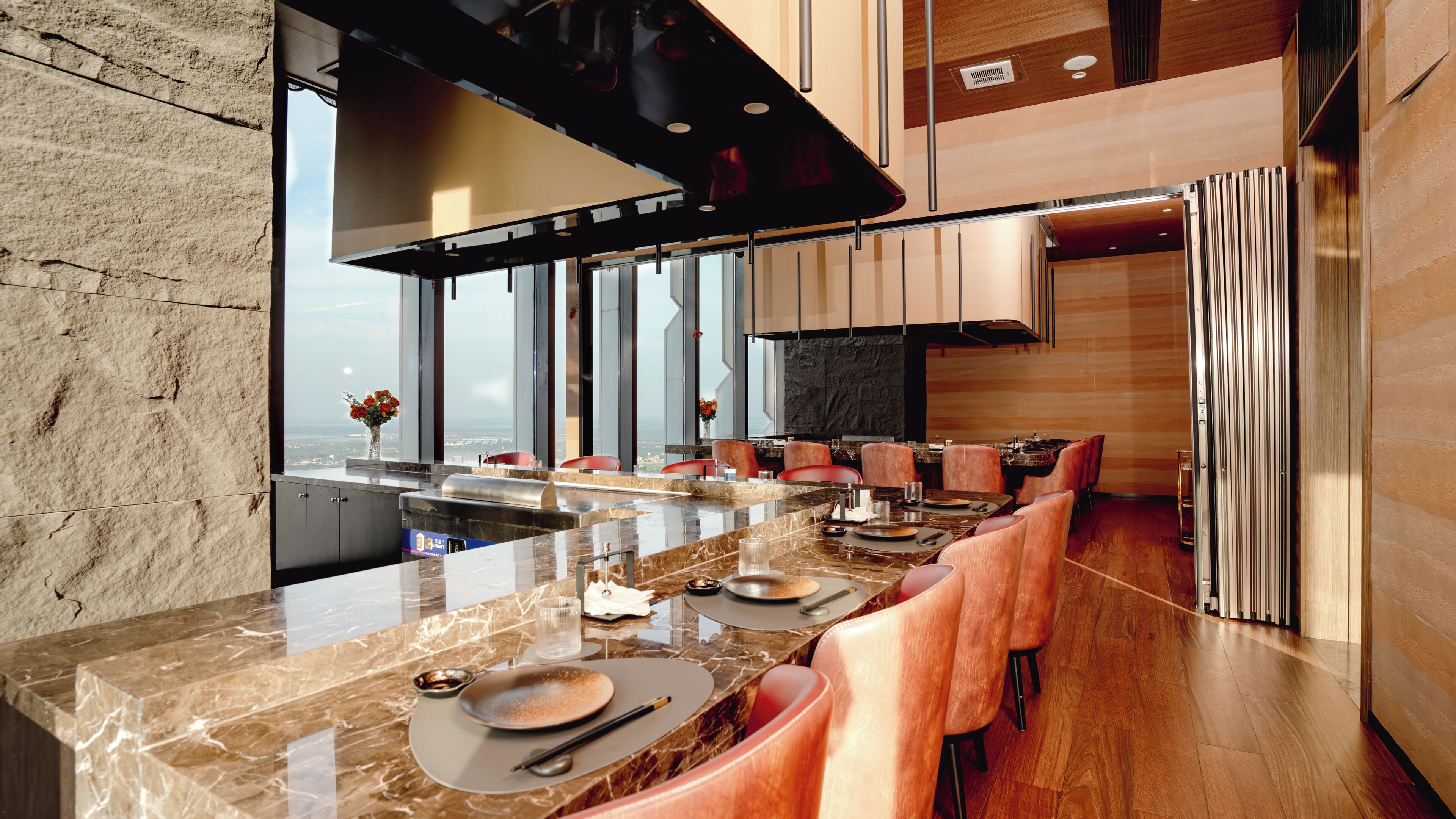 Une cuisine moderne dotée d’un plan de travail en marbre, d’appareils électroménagers en acier inoxydable et offrant une vue sur la ville.