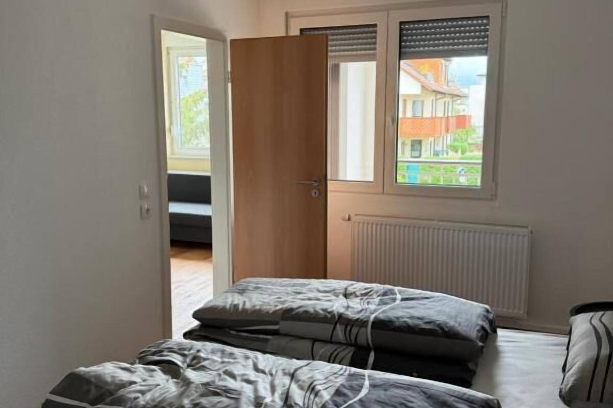 A bedroom with a bed, a window, and a door.