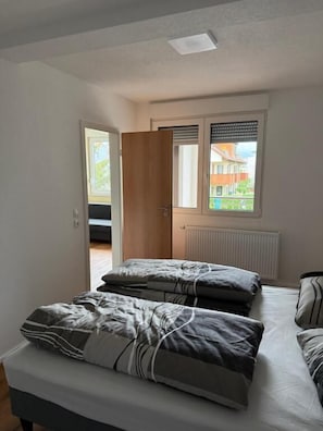A bedroom with a bed, a window, and a door. - Stettenblick Apartments (Loerrach)