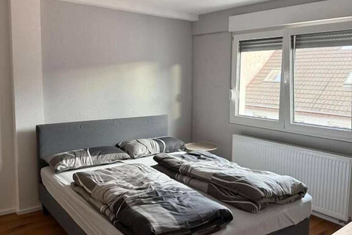A bedroom with a bed, a window, and a radiator.