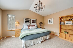 A bedroom with a large bed, a nightstand, a lamp, a bookshelf, and a chandelier. - Hot Tub! Riverfront Family Retreat in Silverthorne (Silverthorne)
