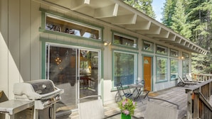 A covered deck with a grill, chairs, and a glass table with a vase. - Near Beaches & Boat Launches! Lake Almanor Getaway (Lake Almanor)
