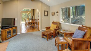 A spacious living room with a large window, a television, and wooden furniture. - Near Beaches & Boat Launches! Lake Almanor Getaway (Lake Almanor)