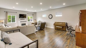 A spacious living room with a sofa, a piano, a television, and a fireplace. - Sunset Soaks & Family Fun: Rural Tennessee Retreat (Bethpage)