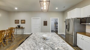 A kitchen with a large island, wooden chairs, a refrigerator, and a pendant light. - Sunset Soaks & Family Fun: Rural Tennessee Retreat (Bethpage)