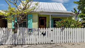 A house with a white picket fence, a metal roof, and a wooden door. - Walk to Southernmost Point! Conch Cottage w/ Patio (Key West)